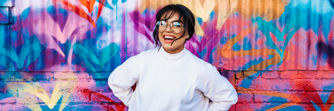 Leende kvinna framför färgglad vägg