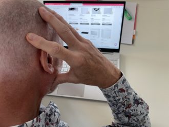 Man som lutar huvudet mot handen framför sin jobbdator