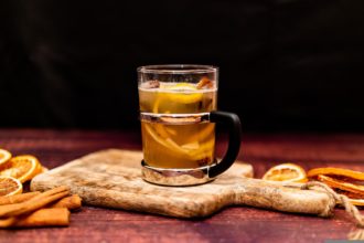Genomskinlig kopp med vit glögg, apelsinskal och kanel