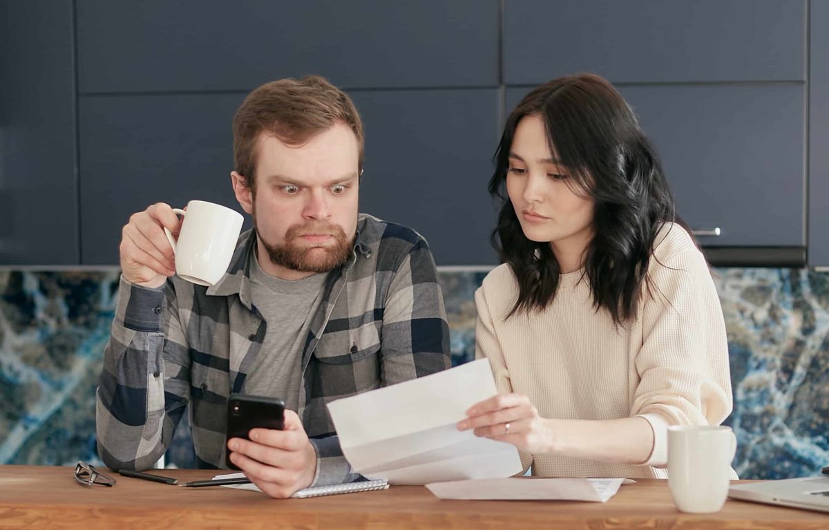 Ett par som kollar på en faktura och ser bekymrade